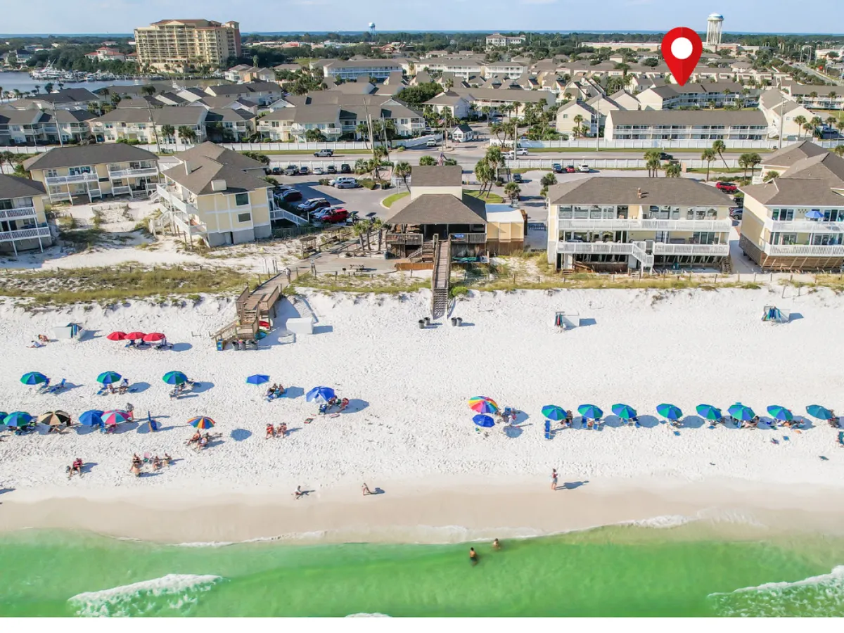 A quintessential beach scene featuring the powdery sands of Destin, emerald waters of the Gulf of Mexico, colorful umbrellas, and people enjoying sunbathing, swimming, and walking along the shoreline. The relaxed mood emphasizes the vibrancy and inviting nature of the beach.