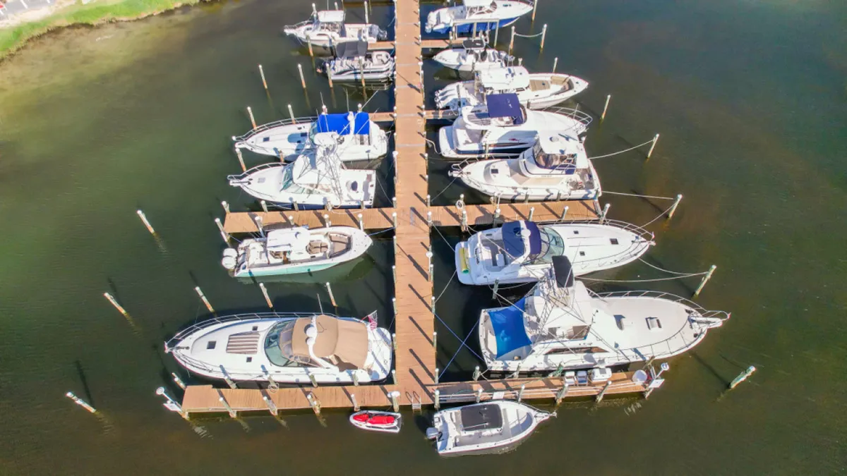 Wooden marina docks stretch into calm greenish water, with luxury boats and yachts moored alongside. The marina scene evokes opportunities for boating, fishing, and water-based recreation, tying in with the section’s focus on exploring Destin’s marinas and coastal activities.